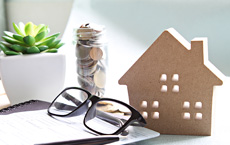 desk with a house modal and a pair of glasses resting on it